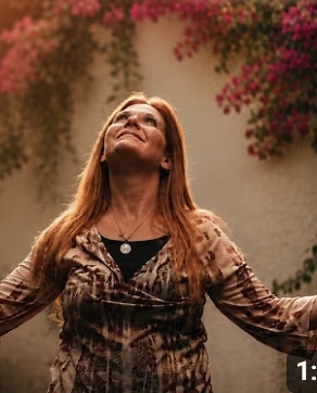 Joan Marie in her garden, arms open to the evening light